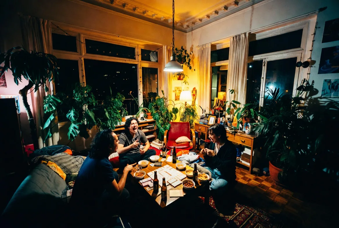 Roomies jugando juegos de mesa de noche en el salón común de un hostal